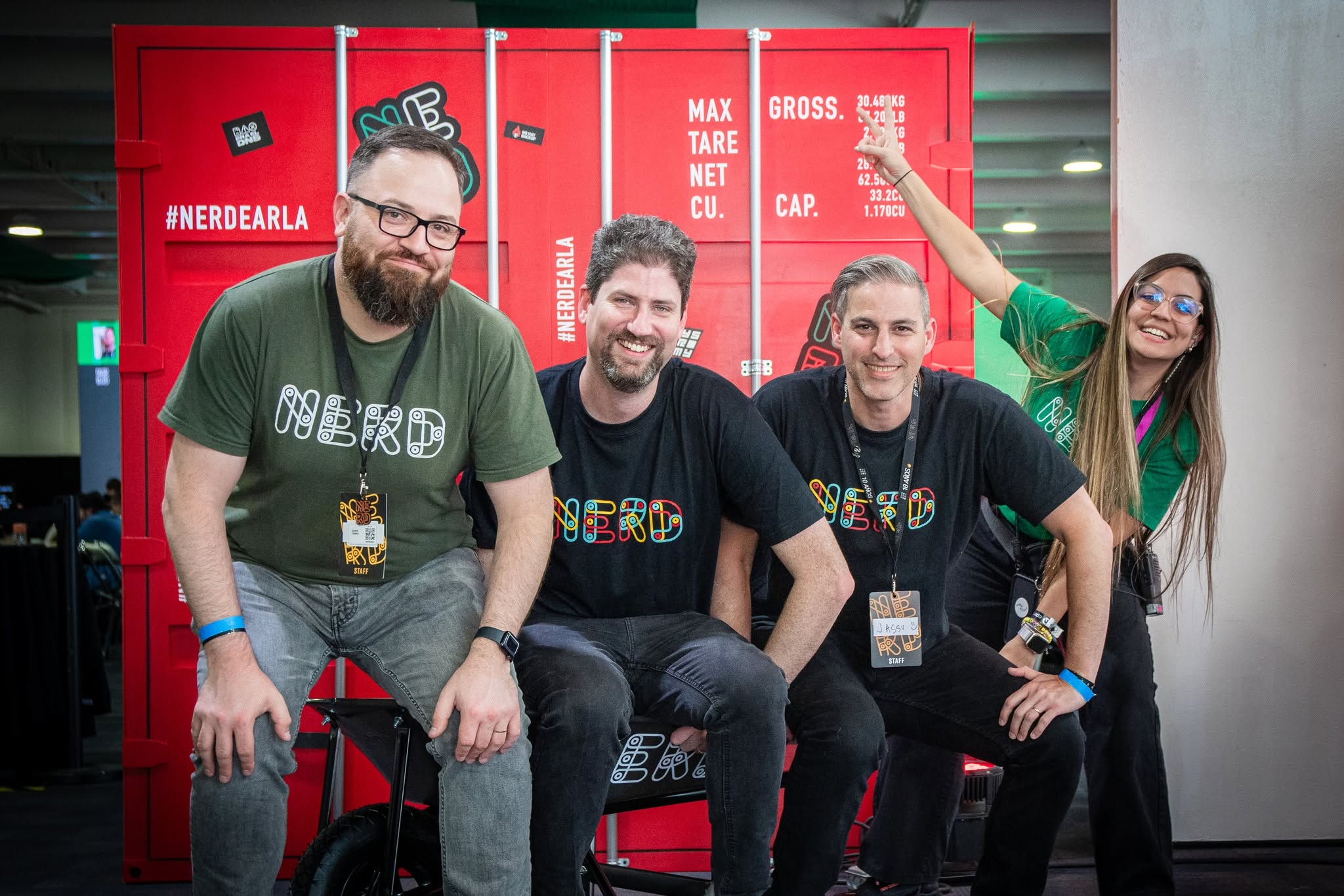 Part of the Nerdearla team poses in front of a red container with the #Nerdearla hashtag