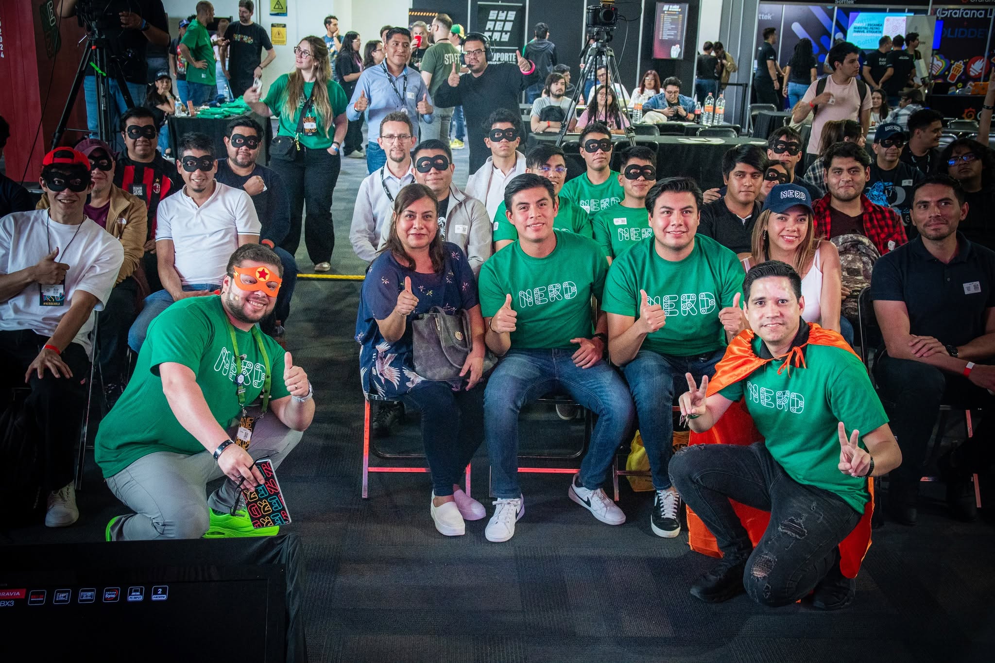 Attendees in NERD T-shirts and eye masks pose as a group in front of the stage